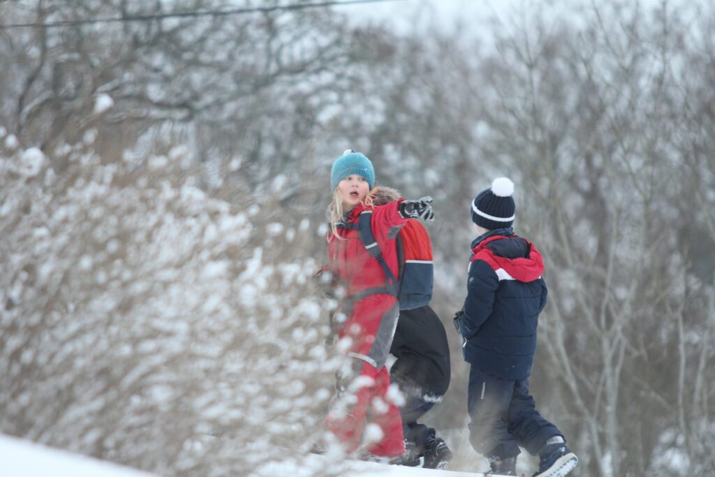 Kolme lasta ulkoilee talvisessa luonnossa